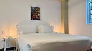 Een net opgemaakt bed met witte lakens in een kamer met witte wanden.