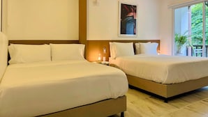 Ein Hotelzimmer mit zwei Betten, einem großen Fenster mit Blick auf Grünflächen und einem gerahmten Bild an der Wand.