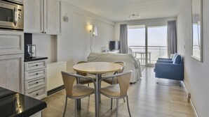 A modern hotel room with a kitchen, dining area, and a balcony with a view. - Apartment in Blankenberge With Sea Views (Blankenberge)