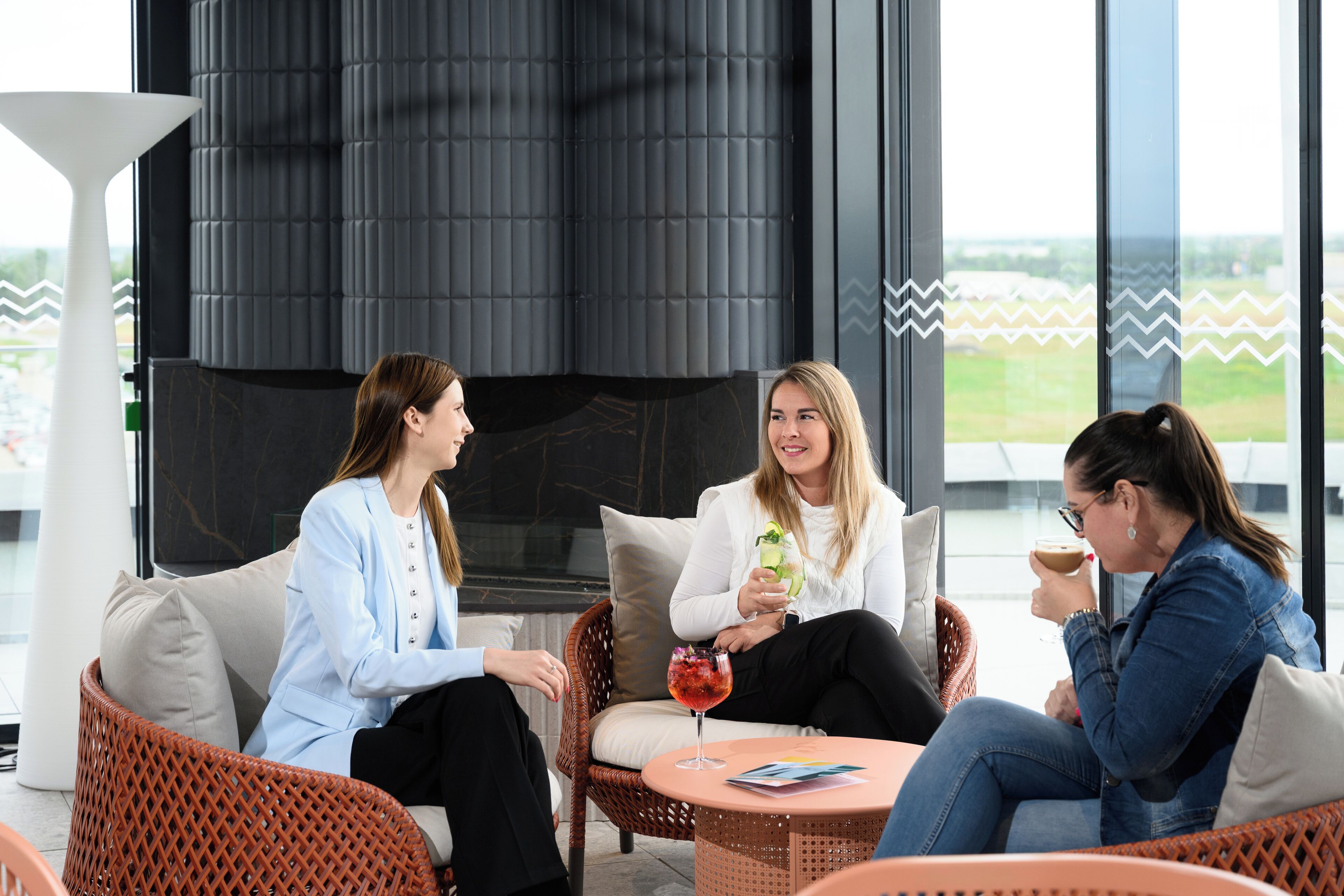 Un área de estar moderna al aire libre con mobiliario de mimbre y una mesa redonda, con vistas panorámicas.