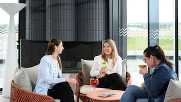 Un área de estar moderna al aire libre con mobiliario de mimbre y una mesa redonda, con vistas panorámicas.