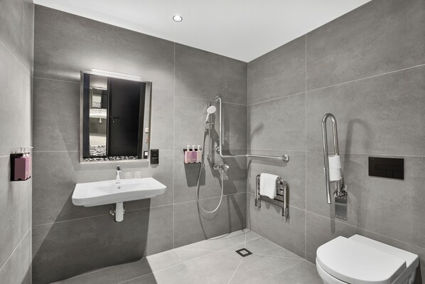 A modern bathroom with a sink, mirror, shower, and toilet. - TRIBE Budapest Airport (Budapest)