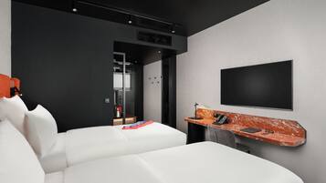 Una habitación de hotel moderna con una cama grande, un escritorio con televisor de pantalla plana y un pequeño rincón de descanso.