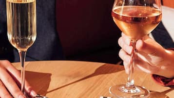 Dos personas sosteniendo copas de vino sobre una mesa de madera con posavasos decorados.