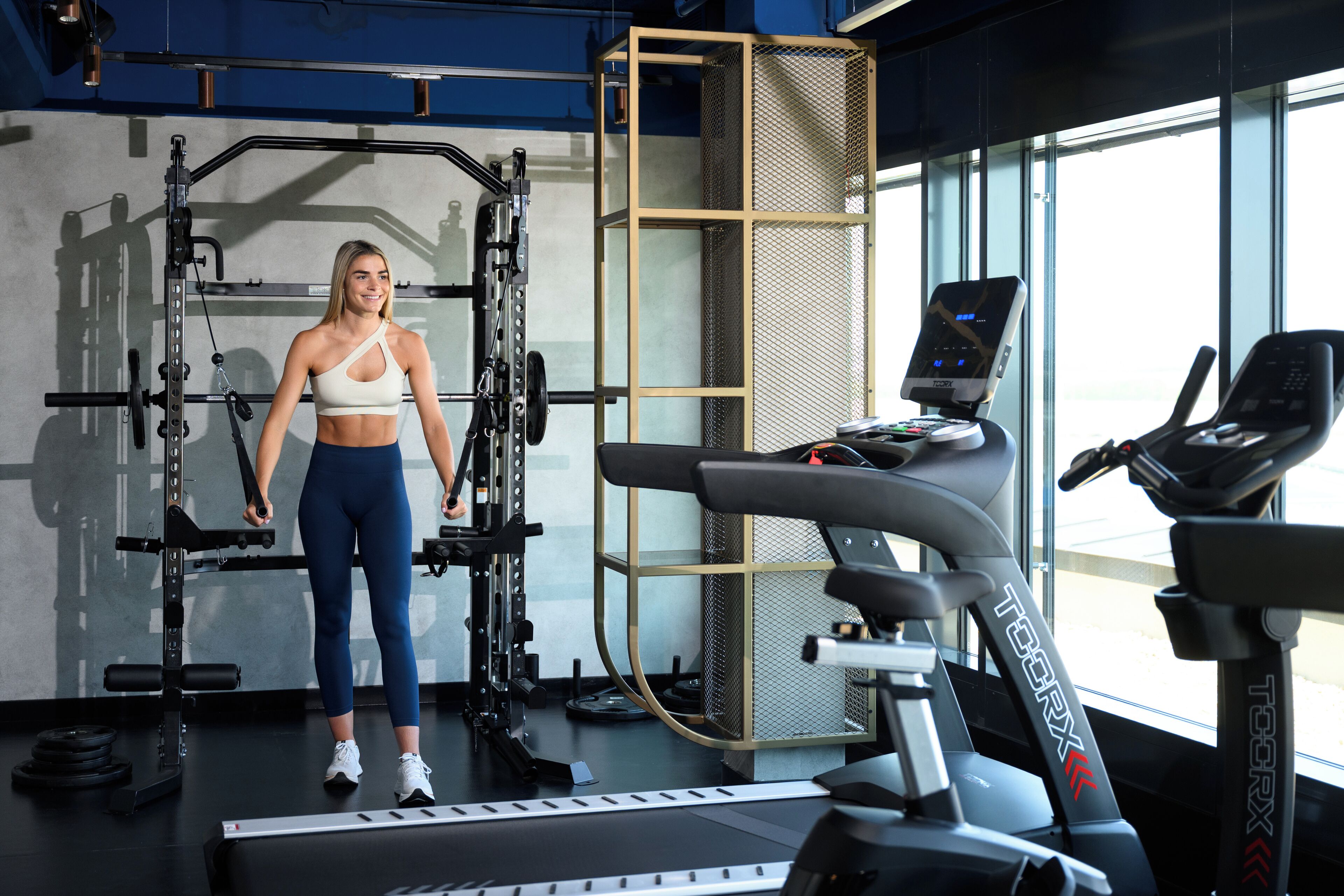 A gym with exercise equipment, including a treadmill and weightlifting station.