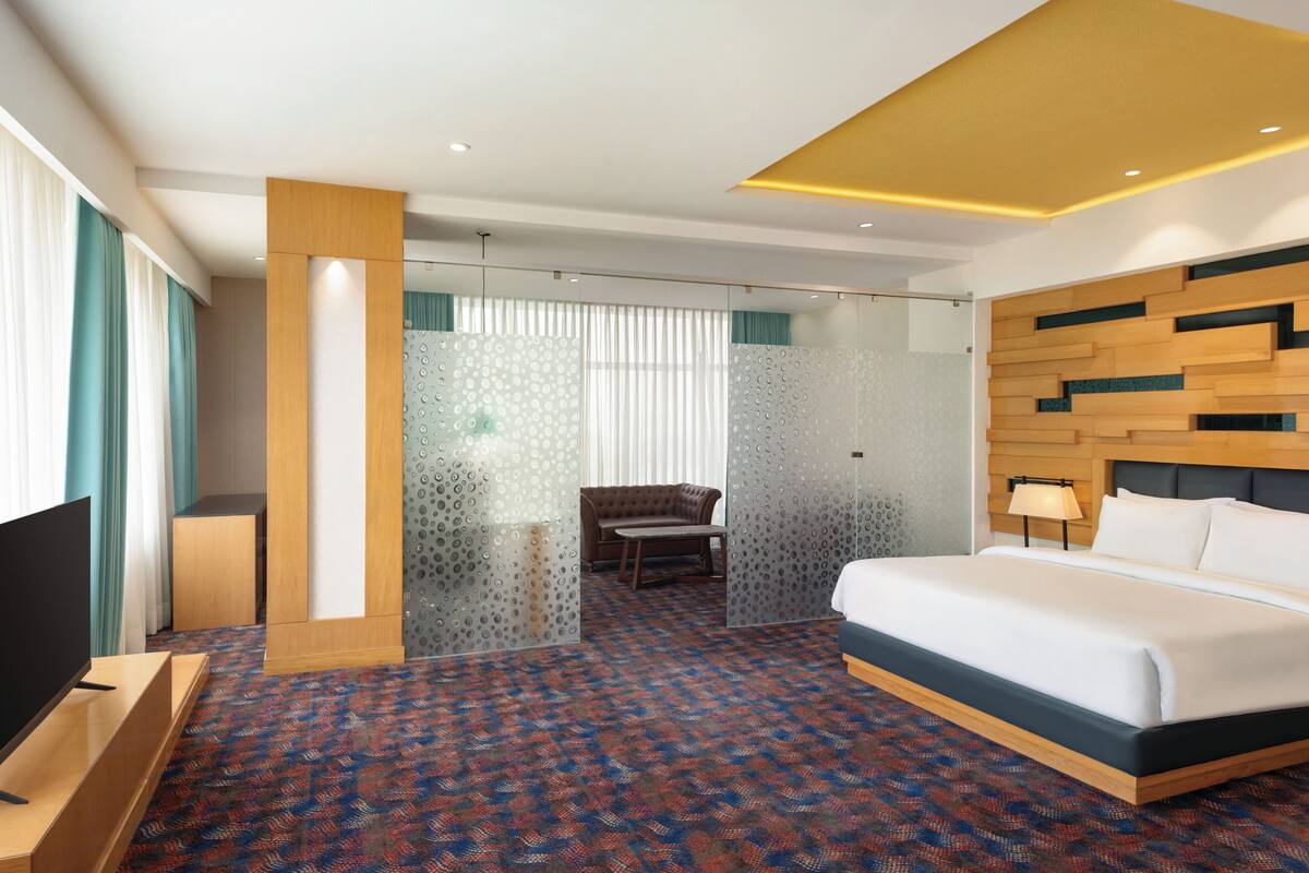 A hotel room with a bed, a TV, a desk, and a chair.