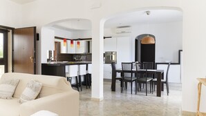 Una sala de estar moderna con un sofá y un comedor con sillas y una mesa.