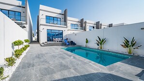A modern poolside area with a clear blue pool, white walls, and a few potted plants. - Blue Marble Beach 4BR Villa with AsstRm,Private Pool and Access to Floating Pier (Fujairah)