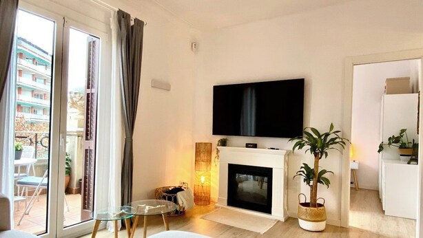Un salon moderne doté d’une cheminée, d’un téléviseur à écran plat et d’un balcon aménagé avec du mobilier d’extérieur.
