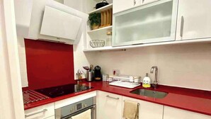 Une cuisine moderne avec des meubles blancs, un plan de travail rouge et un tapis à motifs.
