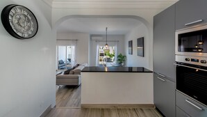 Une cuisine moderne dotée d’un îlot central, d’appareils électroménagers intégrés et donnant sur un espace de vie.