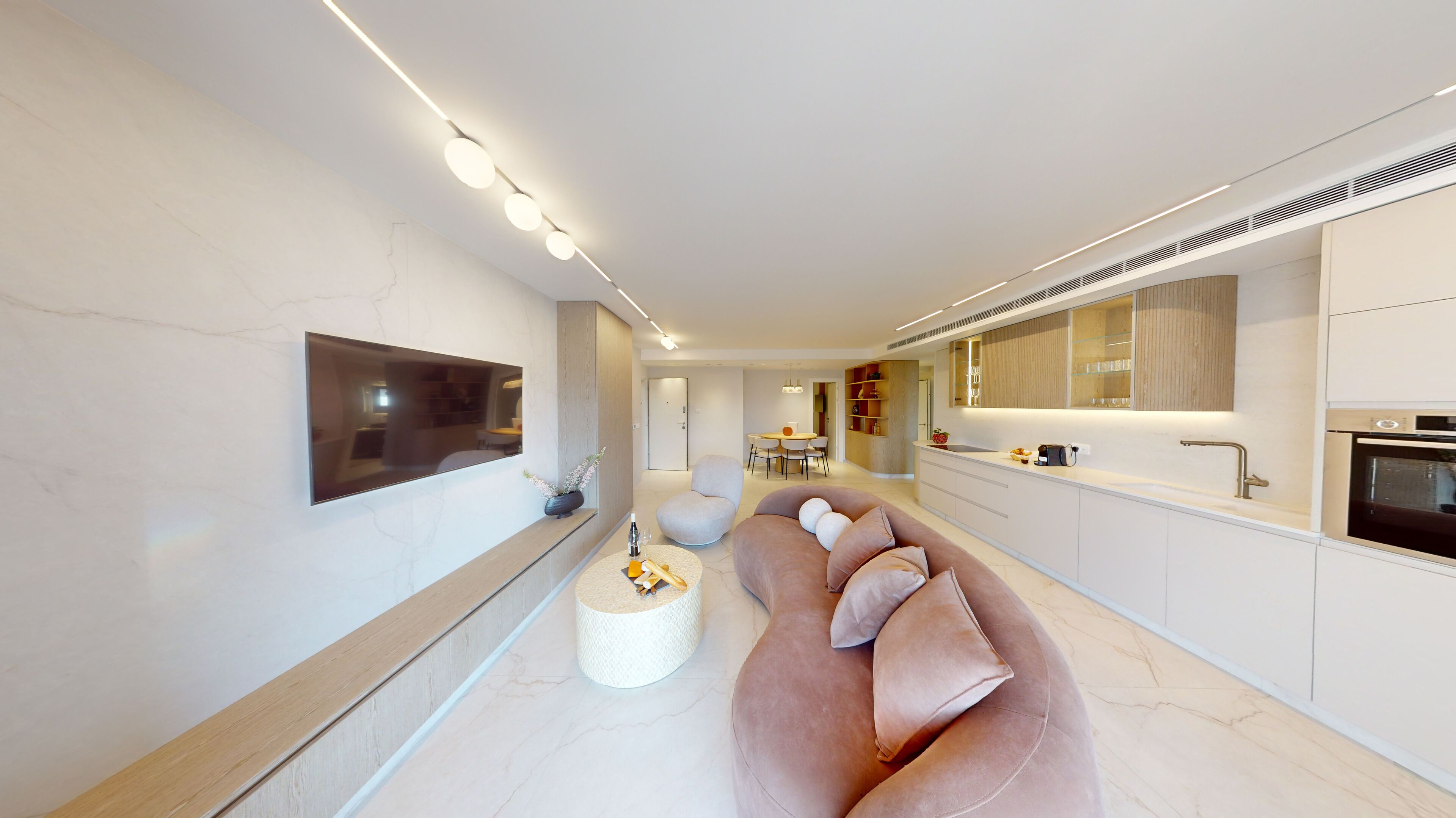 A modern living room with a large flat-screen TV, a pink sofa, and a small round coffee table.