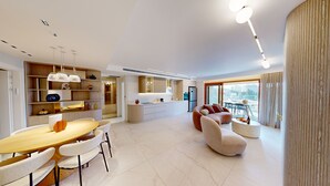 A modern living room with a dining area, a sofa, a coffee table, and a kitchen with a refrigerator. - ★Prestigious King David 3BR/3BA  - View! Pool & Gym★ (Jerusalem)
