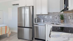 Una cucina moderna con elettrodomestici in acciaio inossidabile, mobili bianchi e una parete rivestita di piastrelle.