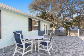 A patio with a round table and four chairs, a light blue building with shutters, and a grill area. - Cozy Condo in Sebastian! (Sebastian)