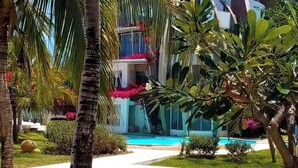 A pool area with a clear view of the pool, surrounded by palm trees and various plants. - Malindi Marine Park 3 bedroom BeachFront (Malindi)