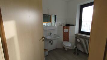 A small, clean bathroom with a sink, toilet, and window.