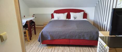 A bedroom with a bed, a desk, and a chair.