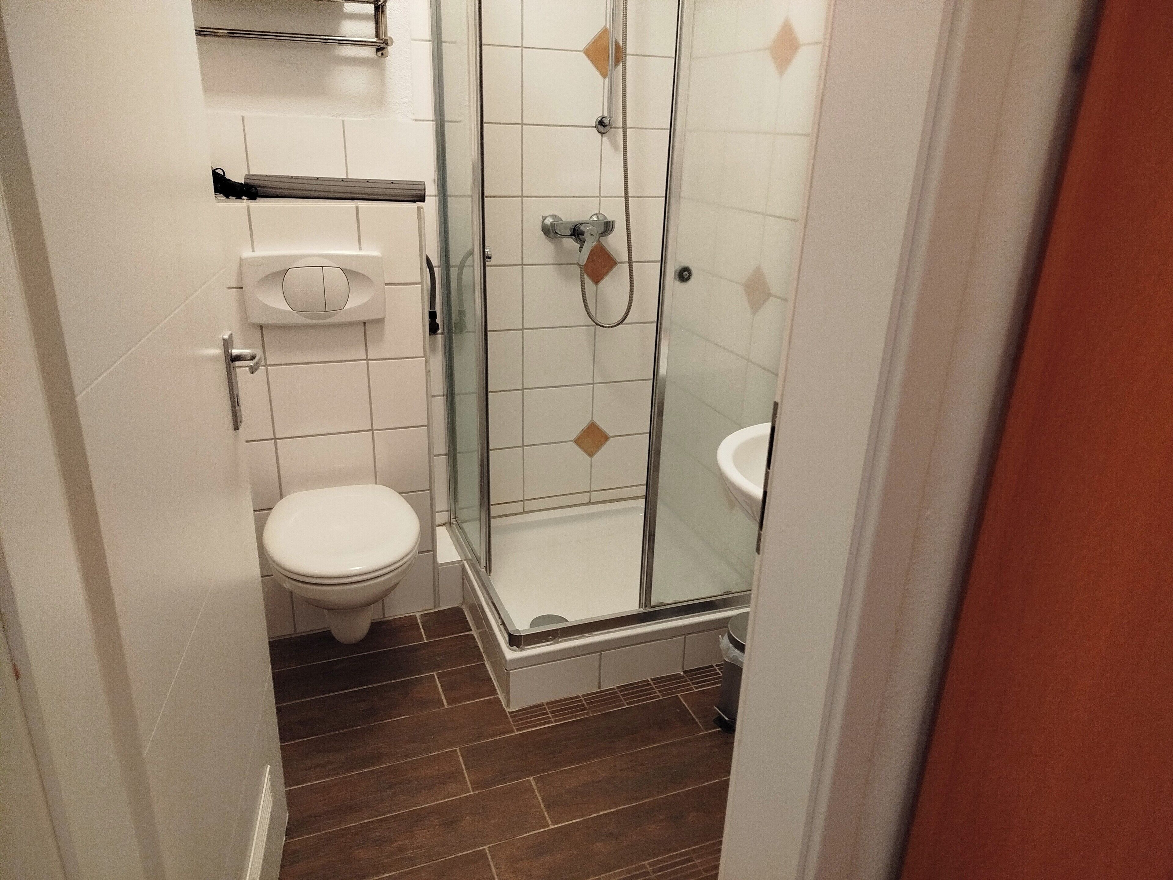 Un baño pequeño con inodoro, lavamanos y ducha con mampara de vidrio.