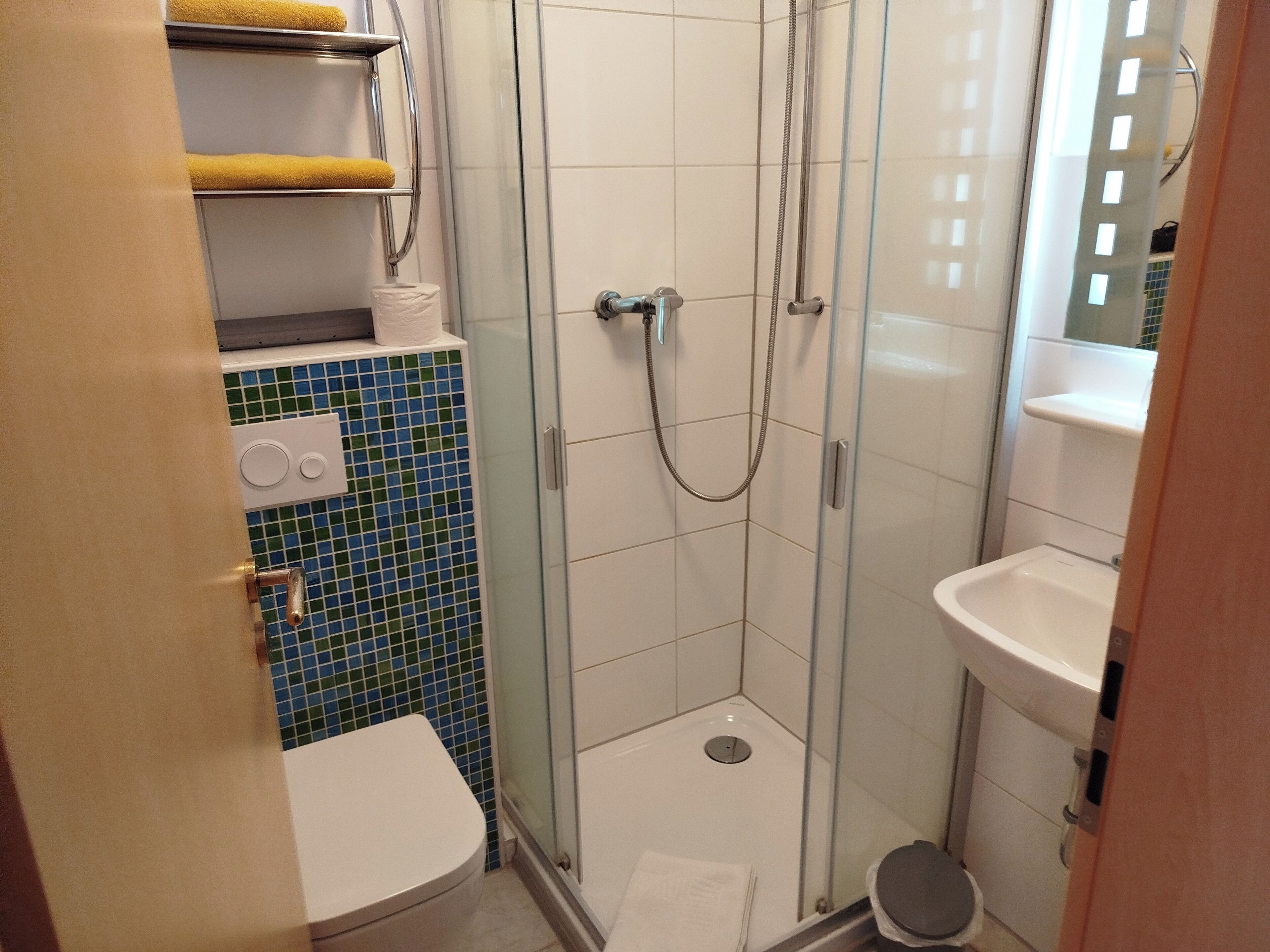 Un baño pequeño con inodoro, cabina de ducha y lavamanos.