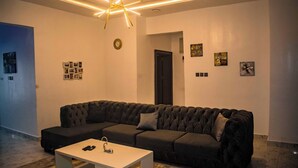 Uma sala de estar moderna com um sofá seccional cinza escuro, uma mesa de centro branca e um lustre de teto exclusivo.