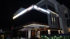 Um edifício moderno com um letreiro iluminado em destaque e uma área de estar coberta.