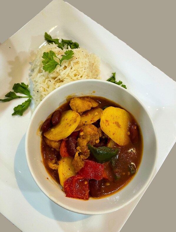 A plate with a bowl of curry and rice, garnished with parsley.