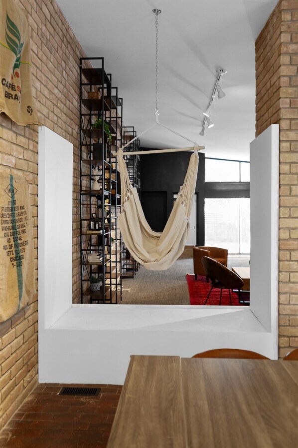 A room with a brick wall, a hammock, a white partition, a wooden table, and a bookshelf. - SPACIOUS 4 Bedroom in the Heart of Tulsa (Tulsa)
