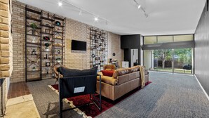 Een moderne woonkamer met een bakstenen muur, een zwarte bank, een rood tapijt en een groot raam.
