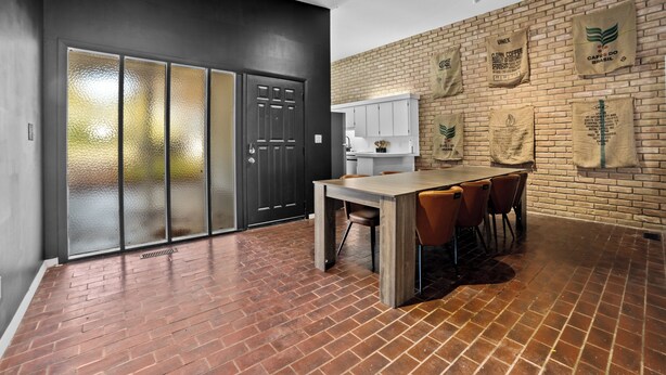 Een moderne keuken met een bakstenen muur, een houten tafel en stoelen.