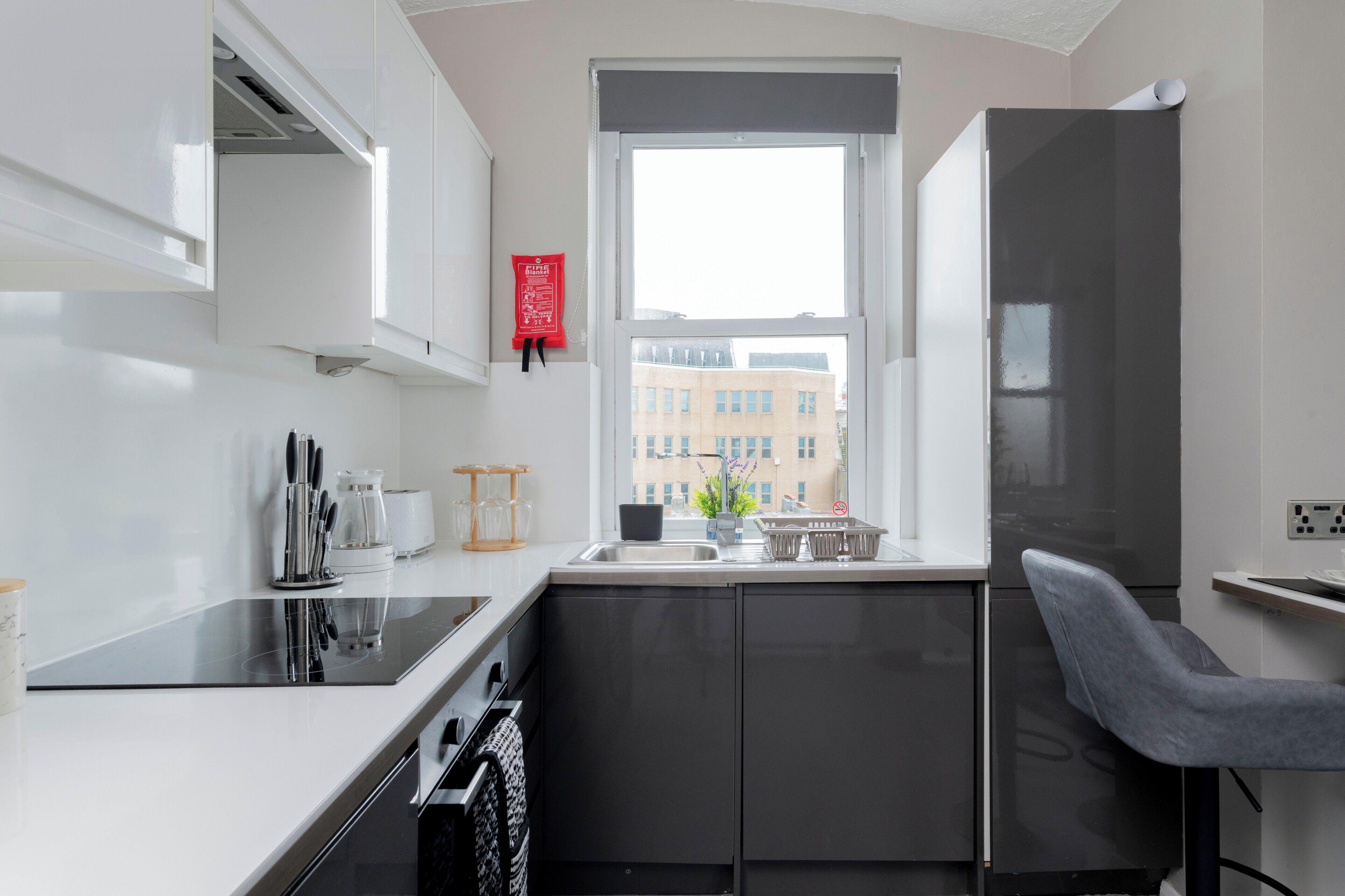 A modern kitchen with a built-in oven, a sink, and a window with a view of buildings.