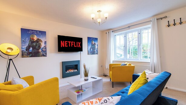 Una sala de estar moderna con un sofá, sillones, una mesa de centro, un televisor y carteles en la pared.