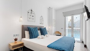 Ein modernes Schlafzimmer mit Bett, Nachttisch und Blick ins Freie.