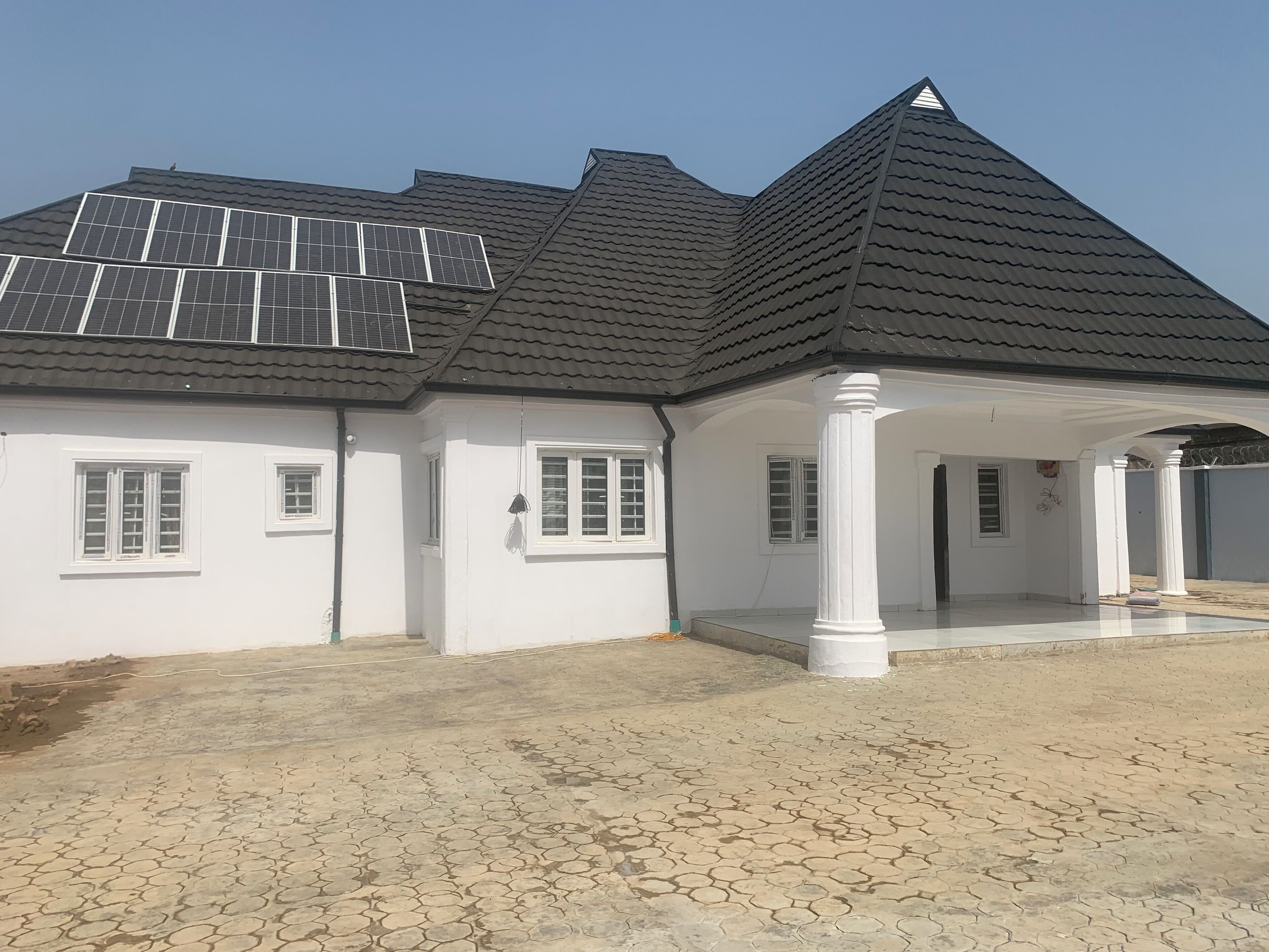Una casa con techo de tejas, paneles solares y un porche cubierto con columnas.