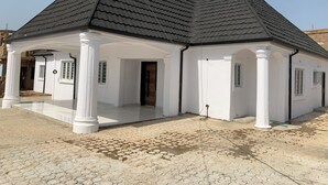 Egy modern ház fekete tetővel, fehér külső falakkal és fedett verandával.