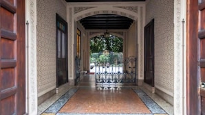 Un pasillo con paredes estampadas y suelo de baldosas que lleva a una entrada con portón.