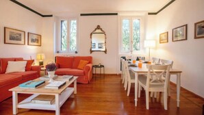 Una sala de estar con un sofá rojo, una mesa de centro, una mesa de comedor con sillas y un espejo en la pared.
