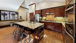 Una cocina moderna con gabinetes de madera, encimeras de granito y electrodomésticos de acero inoxidable.