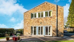 Un bâtiment en pierre de deux étages, doté de grandes fenêtres et d’une allée pavée.