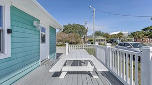 A wooden deck with a white railing, a bench, and a small porch area.