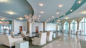 A spacious lobby with modern furniture, a large chandelier, and large windows. - Turquoise Place #1107C | Gulf Front, Private Hot Tub + Resort Amenities (Orange Beach)