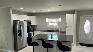 A modern kitchen with a central island, stainless steel appliances, and pendant lighting. - 4-bedroom house on Longboat Key with private beach access only 150 yards away. (Longboat Key)