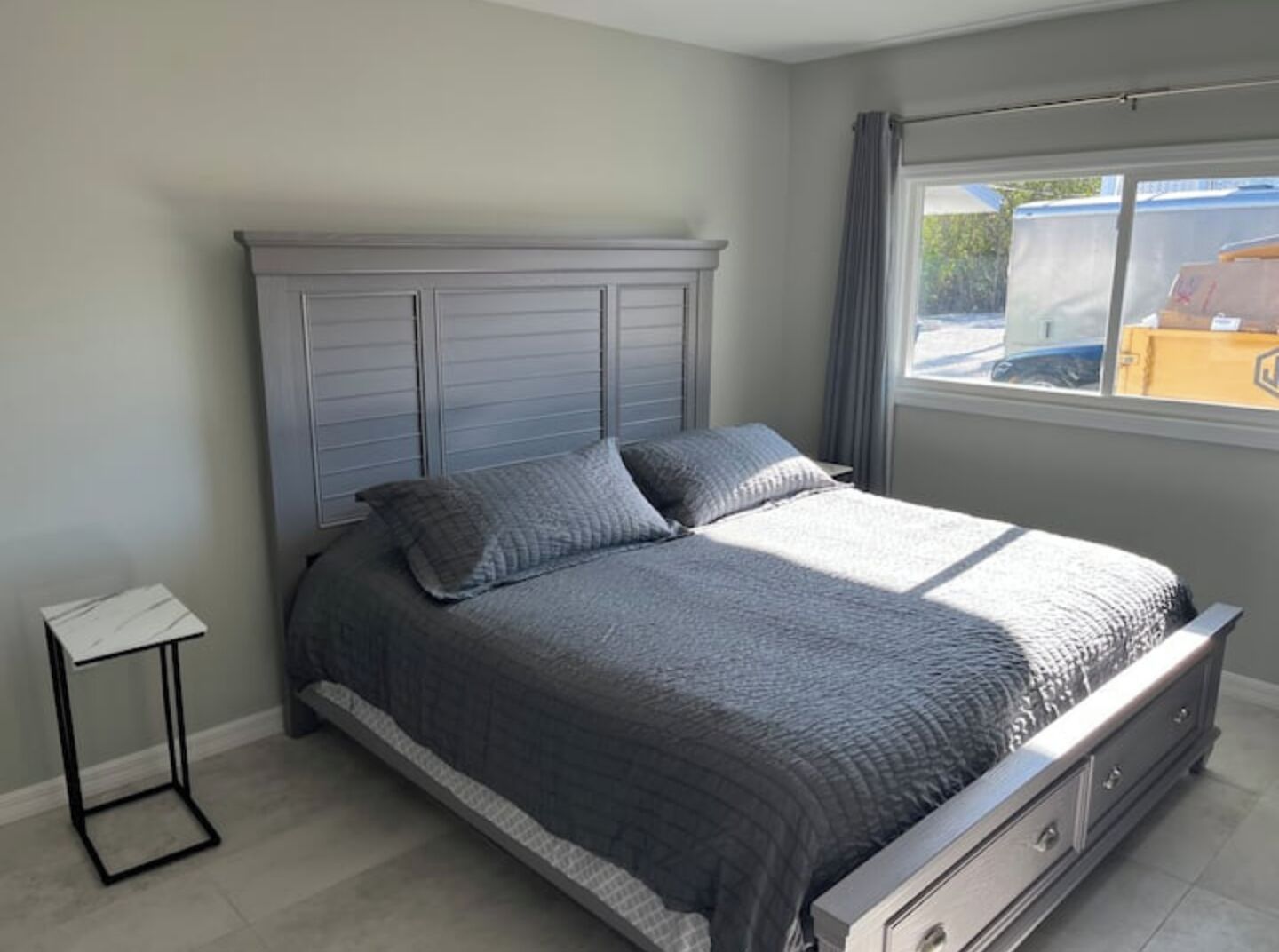 Une chambre à coucher avec un lit, une table de chevet et une fenêtre avec des rideaux.