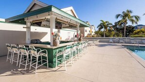 A poolside bar with outdoor seating and a covered area, surrounded by palm trees and a clear sky. - 4-bedroom house on Longboat Key with private beach access only 150 yards away. (Longboat Key)