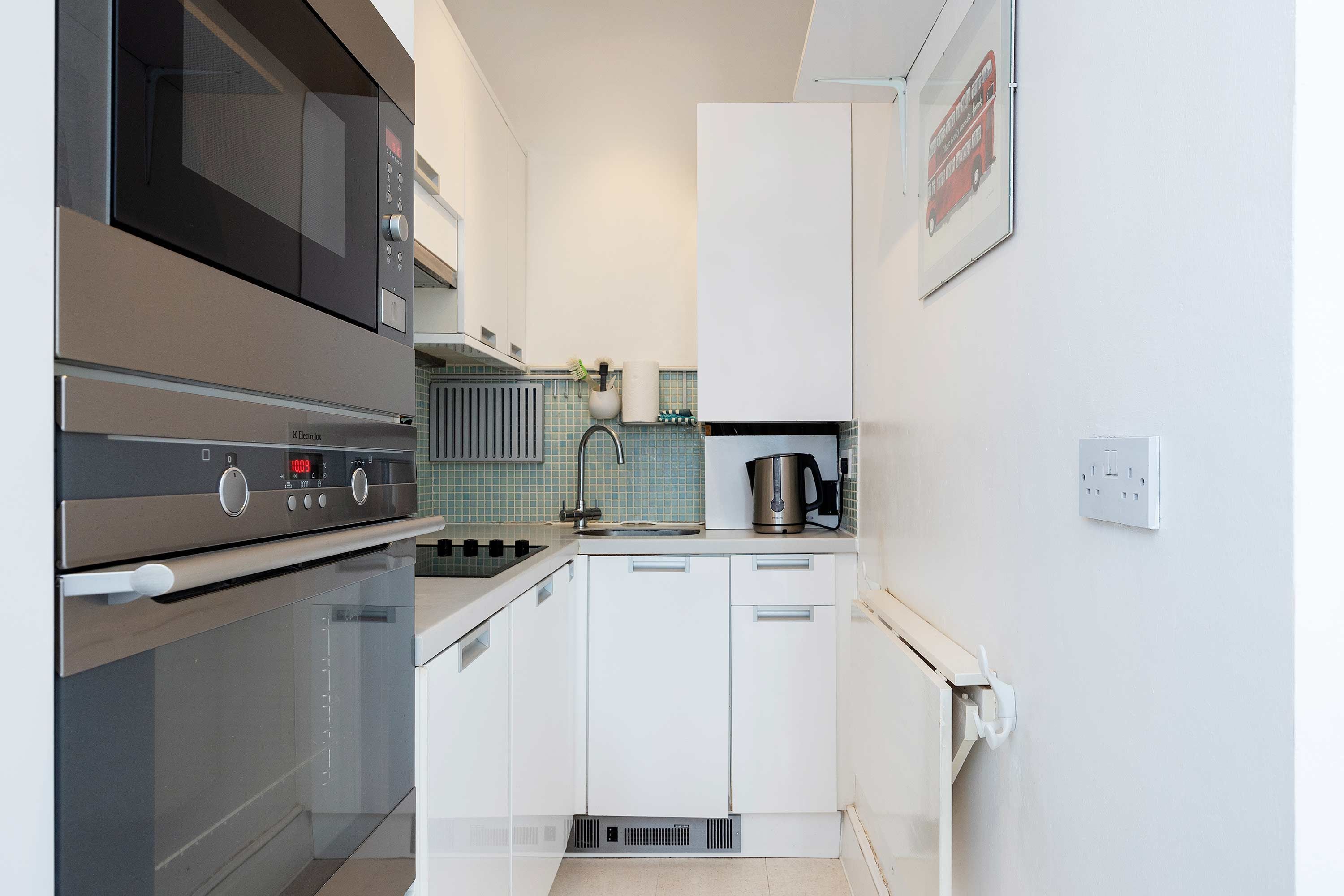 A modern kitchen with stainless steel appliances, white cabinetry, and a tiled backsplash.