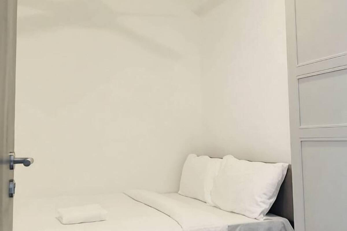 Une pièce avec un lit, une porte et un mur.