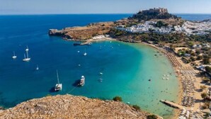 Un pueblo costero con un castillo histórico, aguas turquesas cristalinas y una playa de arena.