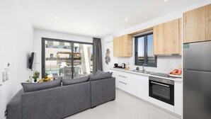 Una cocina moderna con armarios blancos, un refrigerador de acero inoxidable y un amplio ventanal con vista a una piscina.