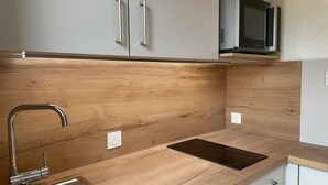 Eine Küche mit Holzausziehtisch, Edelstahlspüle und weißen Schränken.