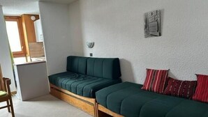 Ein kleines Zimmer mit Schlafsofa, Tisch und Stuhl.
